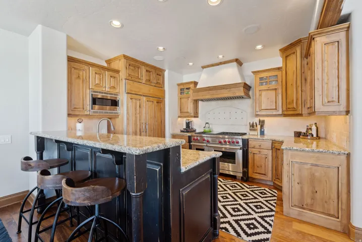 Kitchen featuring a breakfast bar, a peninsula, stainless steel appliances, light stone countertops, and backsplash