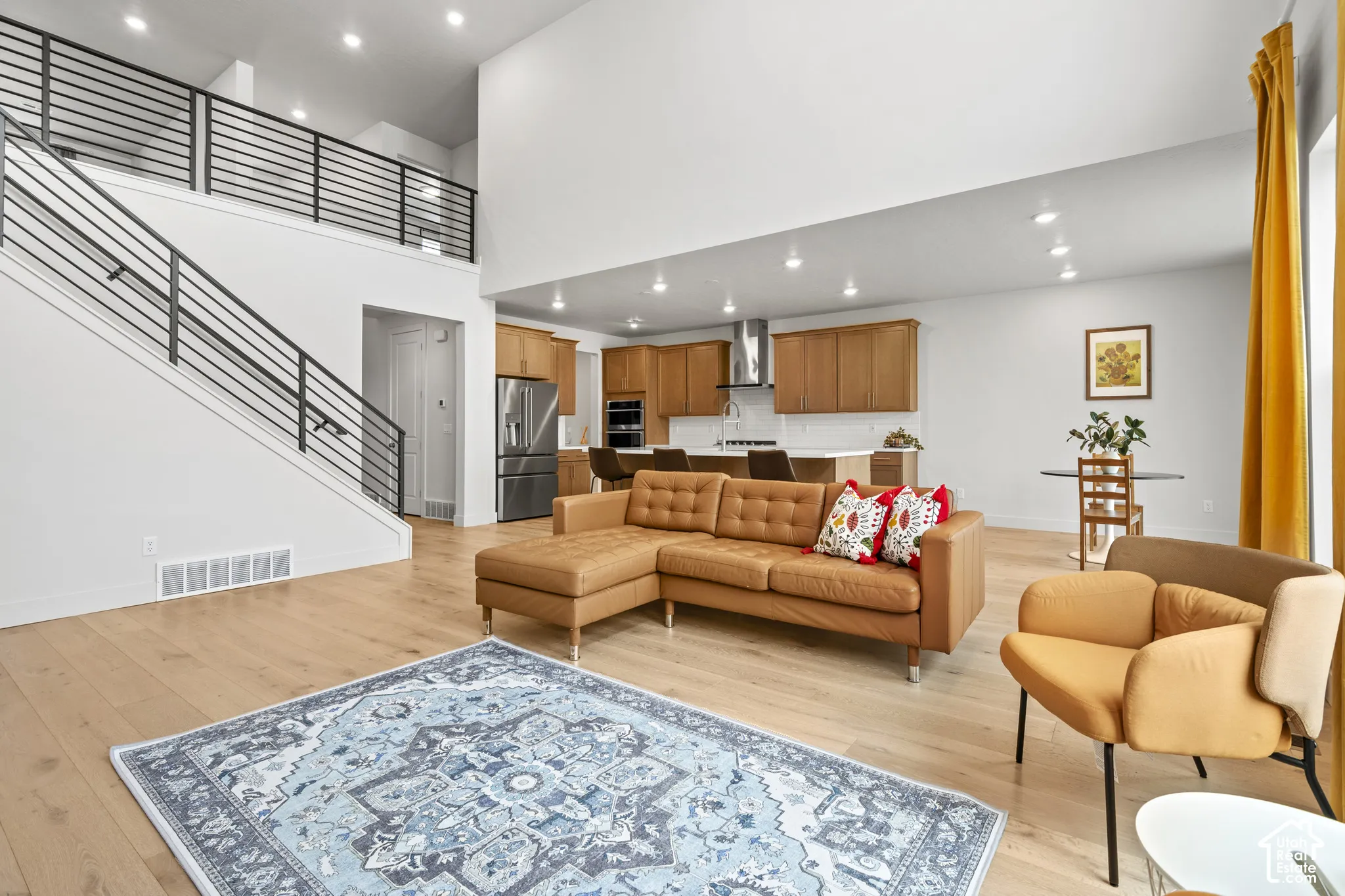 Living area with light LVP wood  floors, recessed lighting, and a high ceiling