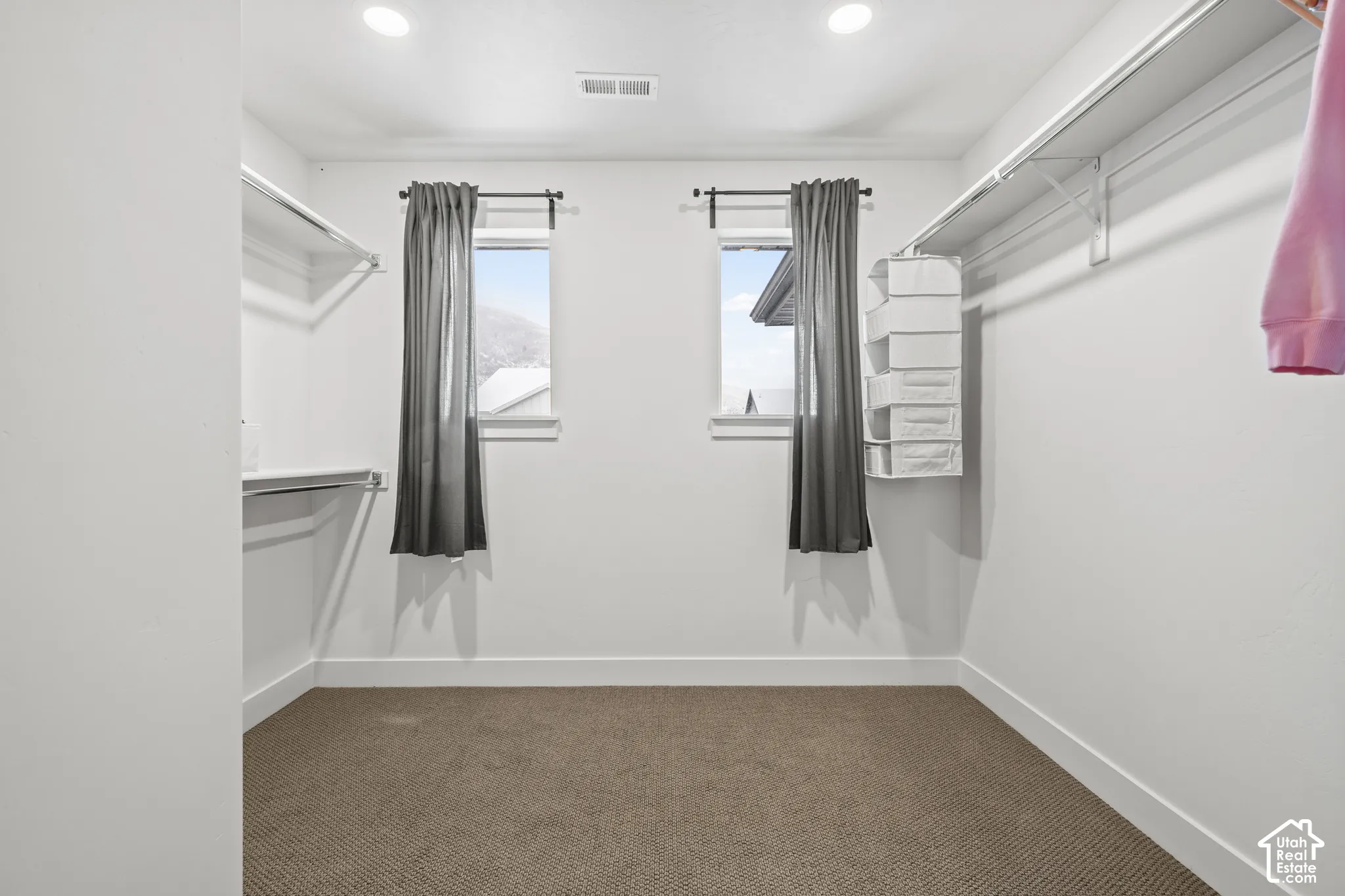 Walk in closet featuring windows and built in shelving.