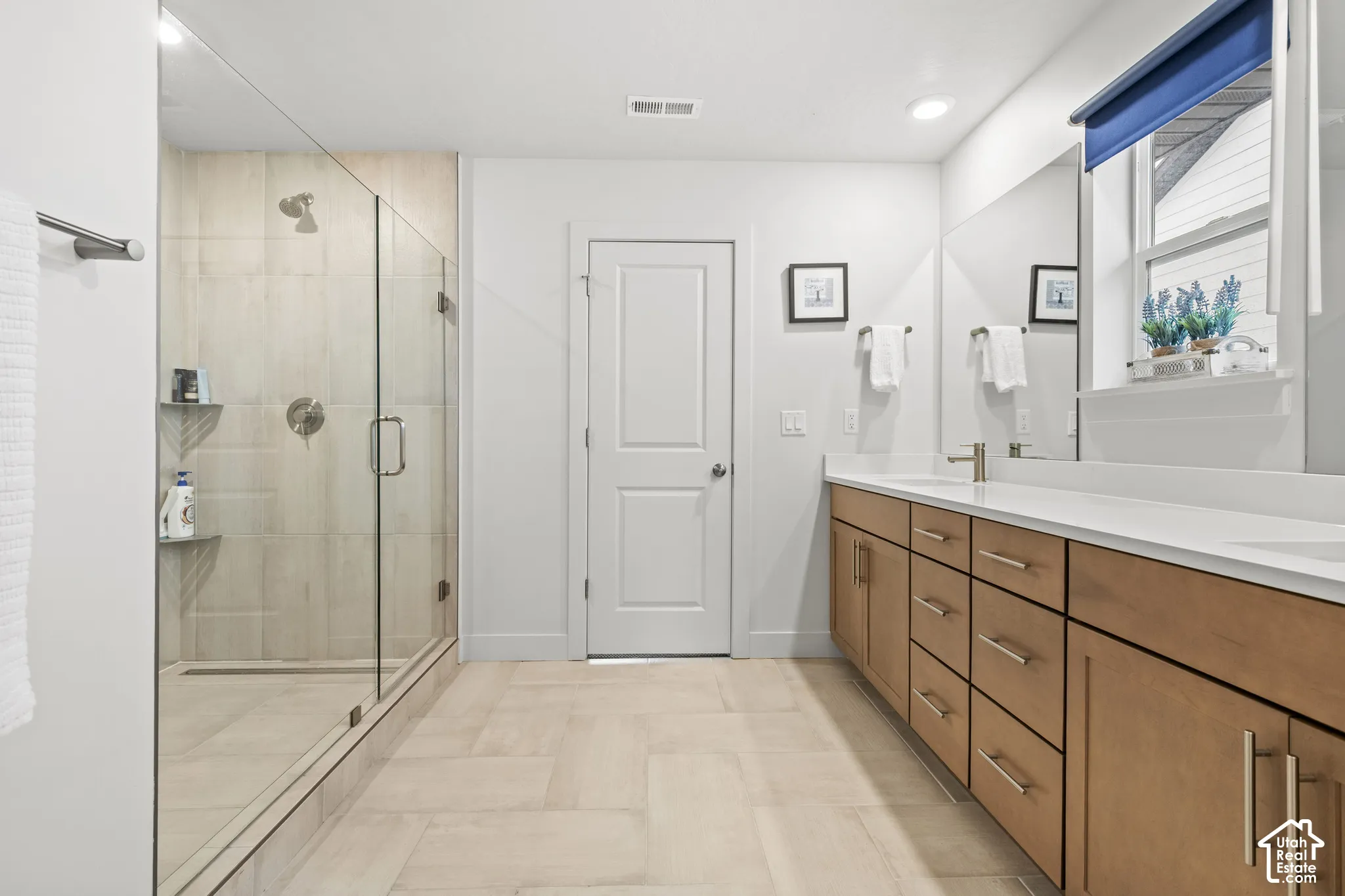 Full bathroom featuring double vanity, a glass stall shower, and recessed lighting