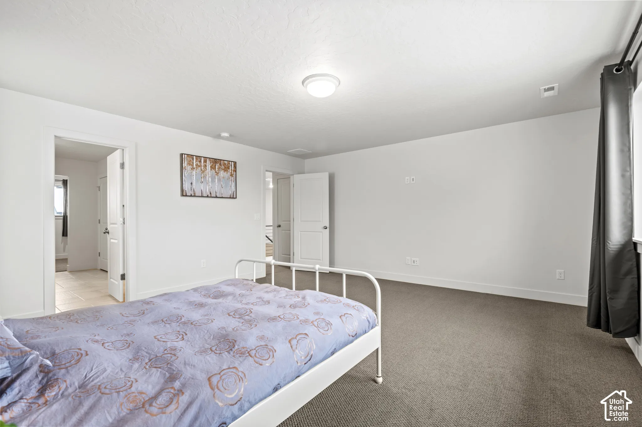 Bedroom with light colored carpet, ensuite, and baseboards