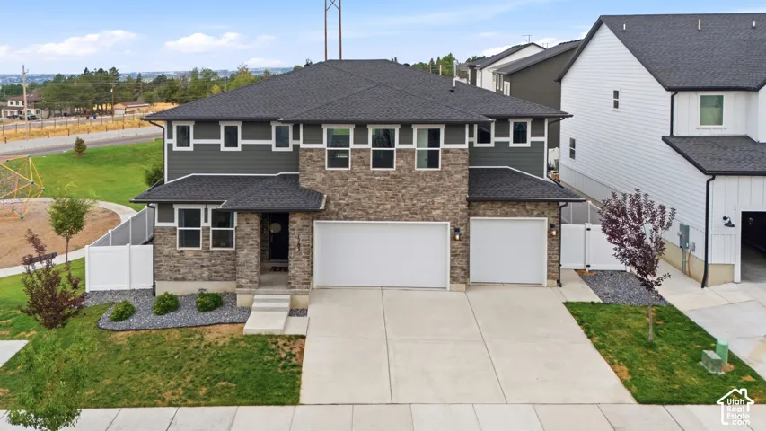 Two-story exterior with stone and horizontal siding, dual garage doors, and a concrete driveway