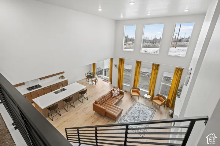 View from loft area of living room with light LVP wood flooring, a high ceiling, and recessed lighting
