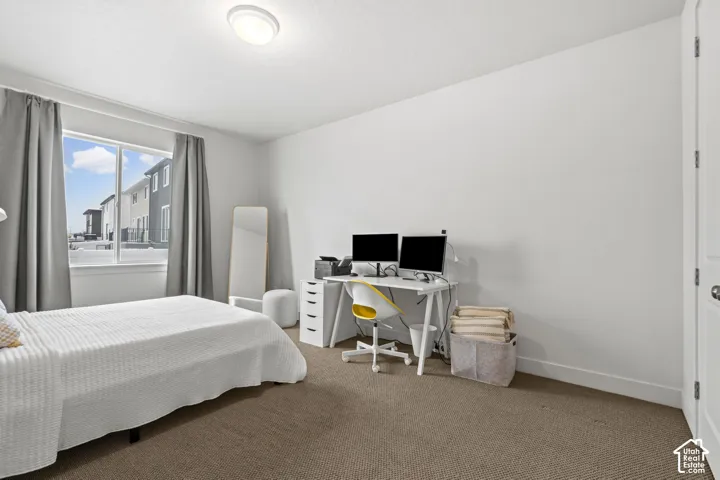 Bedroom featuring light colored carpet and an office area