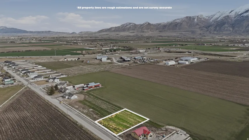 Aerial view of sparsely populated area featuring extensive farmland, a mountain backdrop, and property parcel outlined