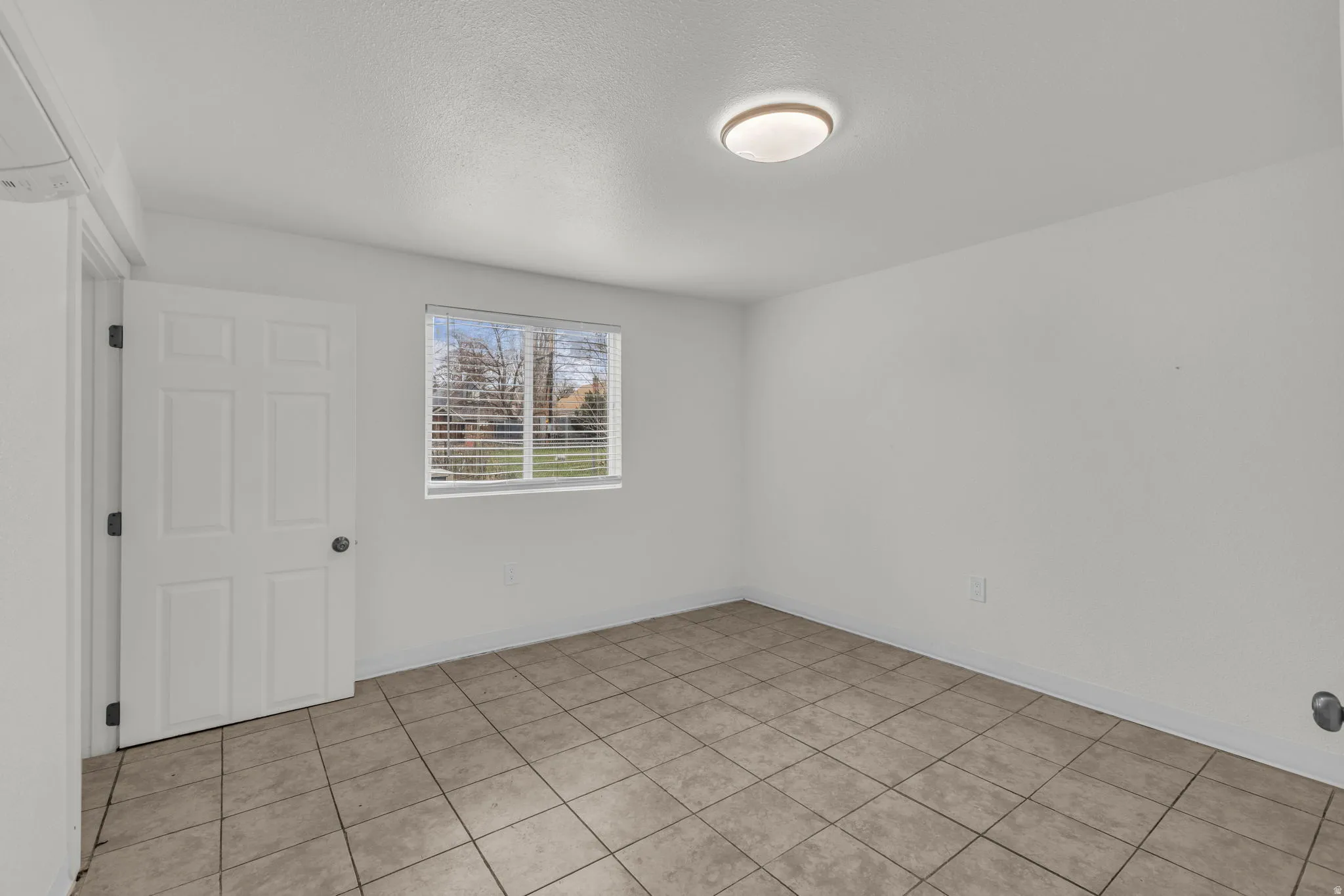 Unfurnished room featuring a textured ceiling and light tile patterned flooring