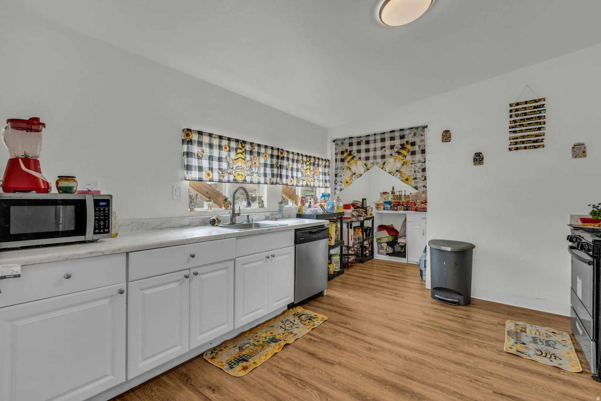 Kitchen with white cabinetry, light countertops, stainless steel appliances, light wood finished floors, and vaulted ceiling