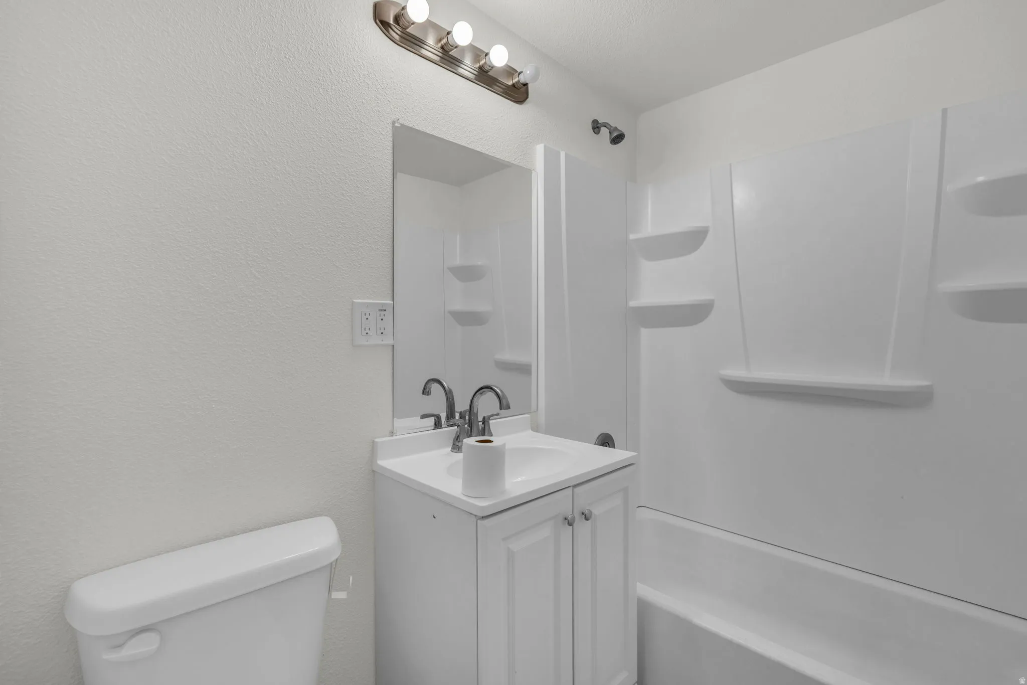 Bathroom with vanity, a textured wall, and shower / washtub combination