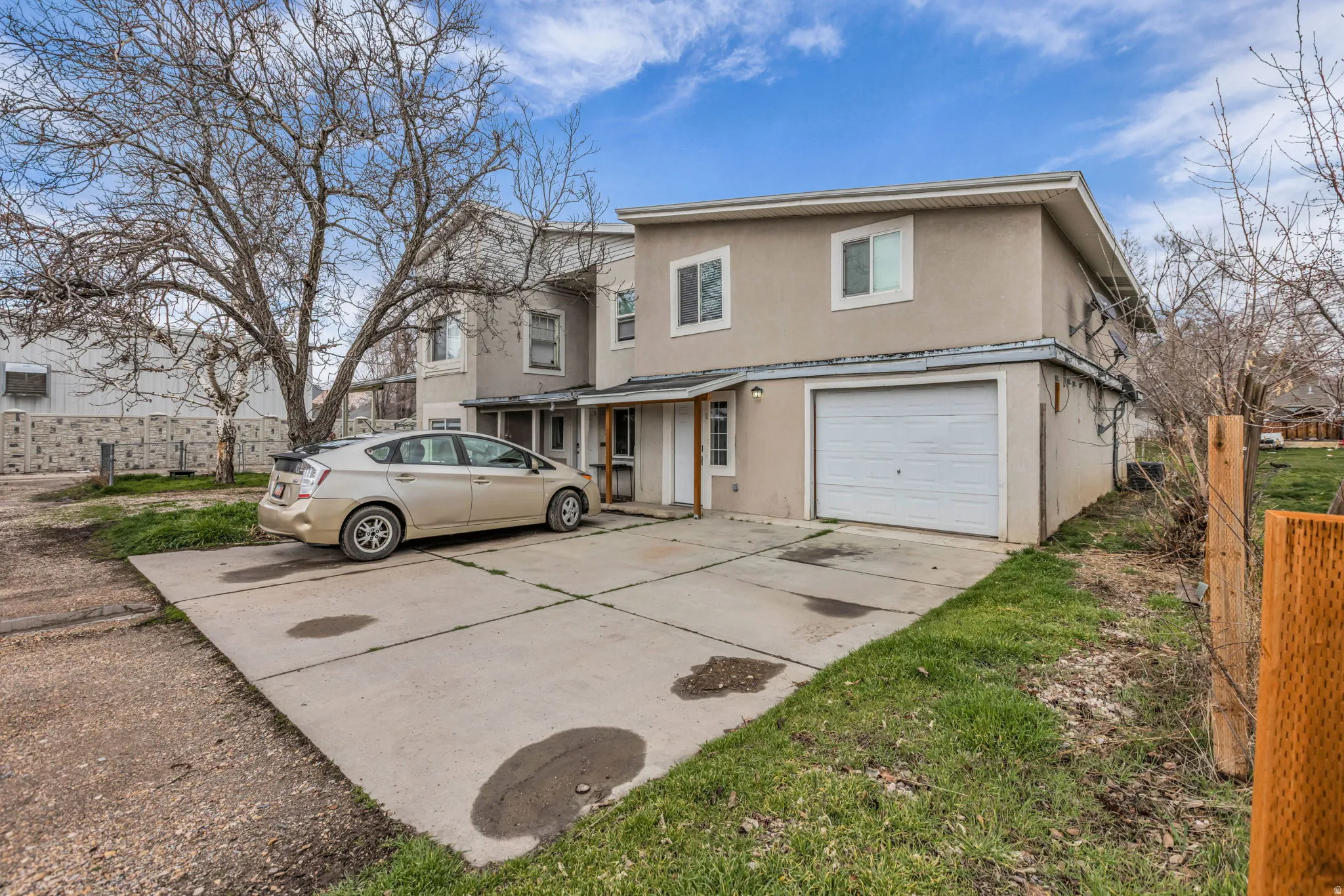 Traditional-style house with stucco siding, an attached garage, and concrete driveway