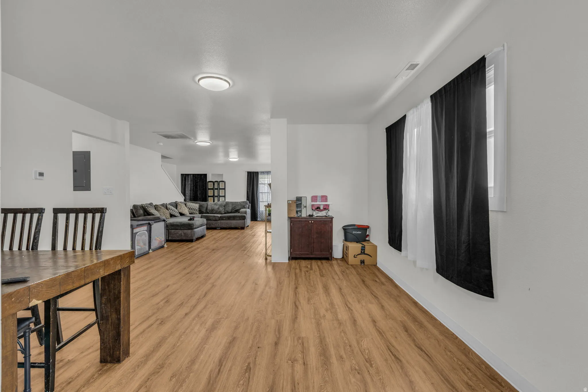 Living room with light wood-style flooring and electric panel