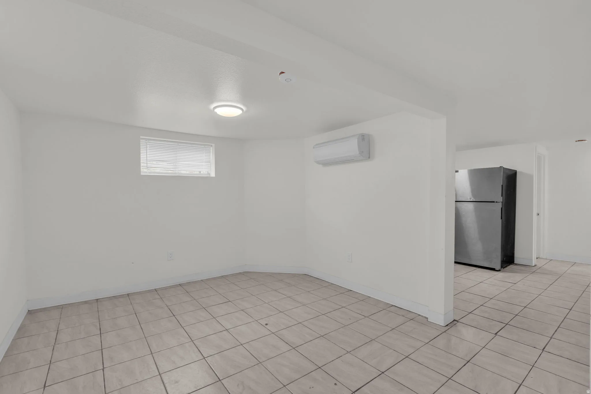 Empty room with light tile patterned flooring and baseboards