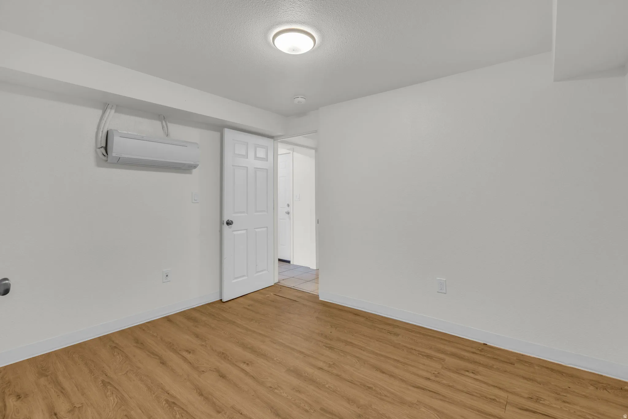 Unfurnished room with light wood-style floors and a textured ceiling