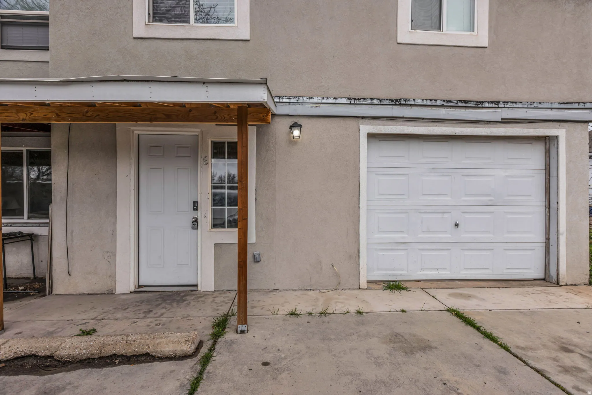 Doorway to property featuring stucco siding, a garage, and driveway