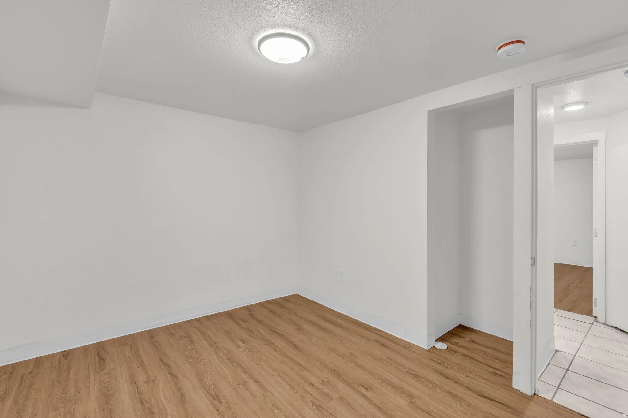 Empty room with light wood-type flooring and a textured ceiling