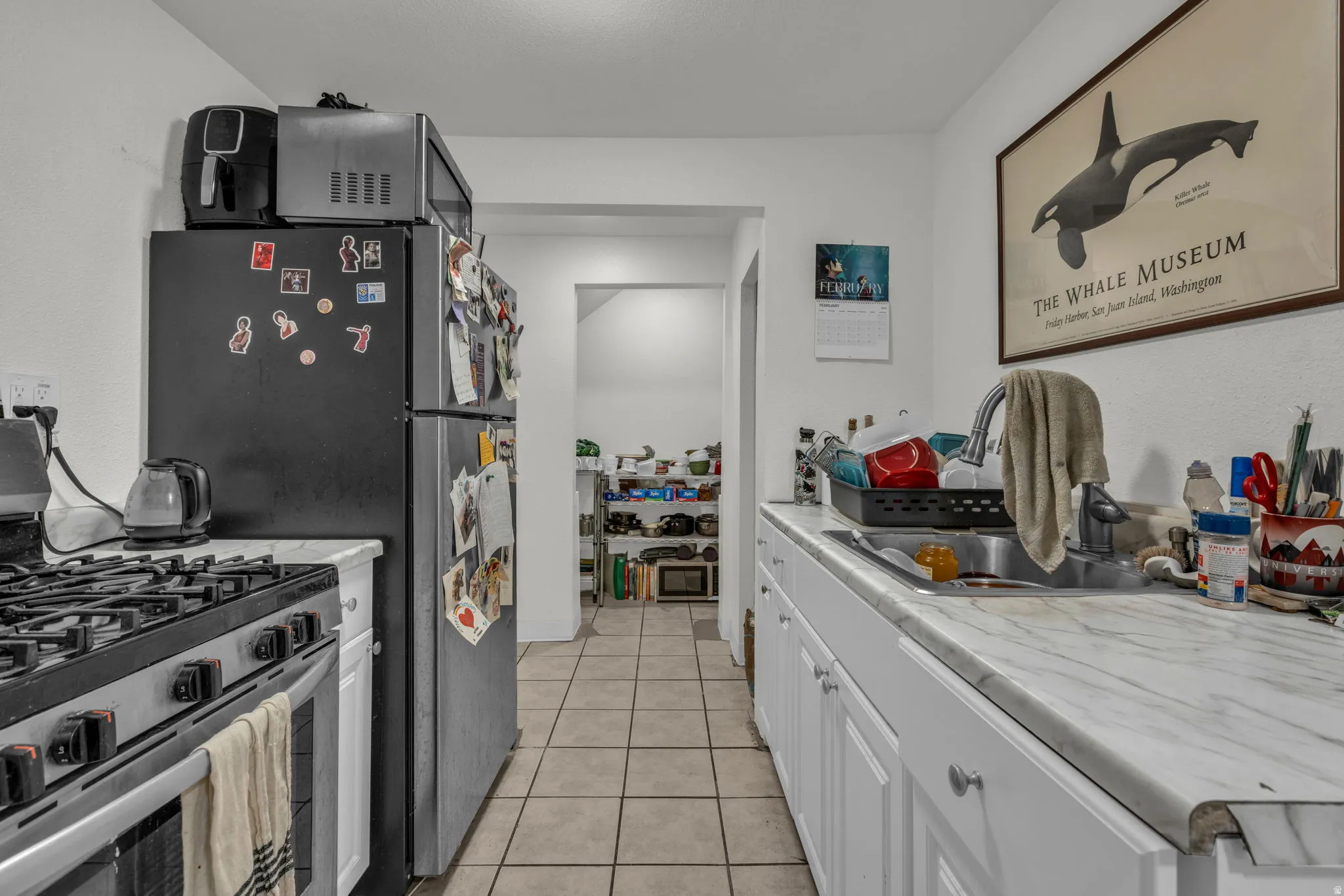 Kitchen featuring stainless steel appliances, light countertops, light tile patterned flooring, and white cabinetry