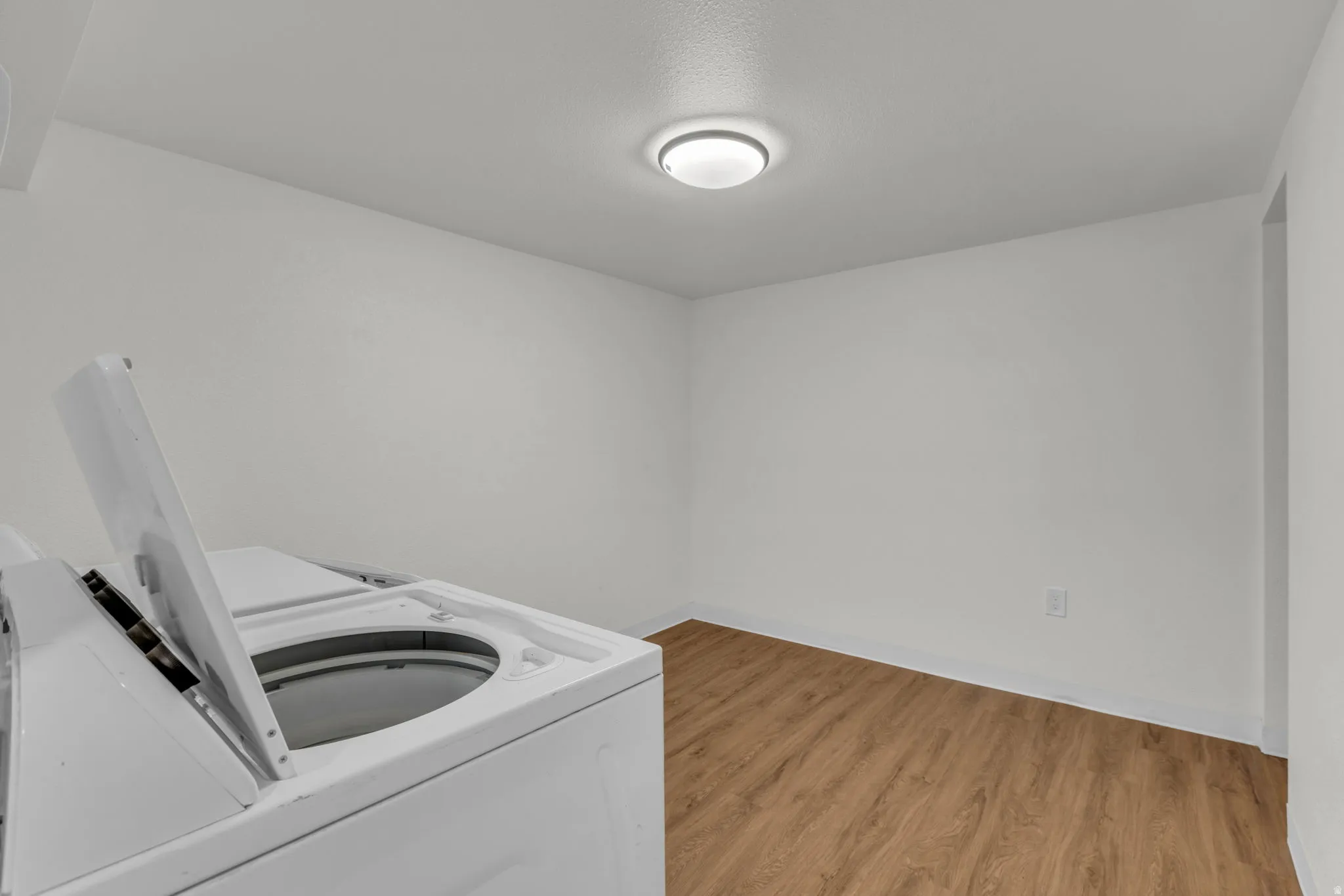 Laundry area featuring light wood finished floors and washing machine and dryer