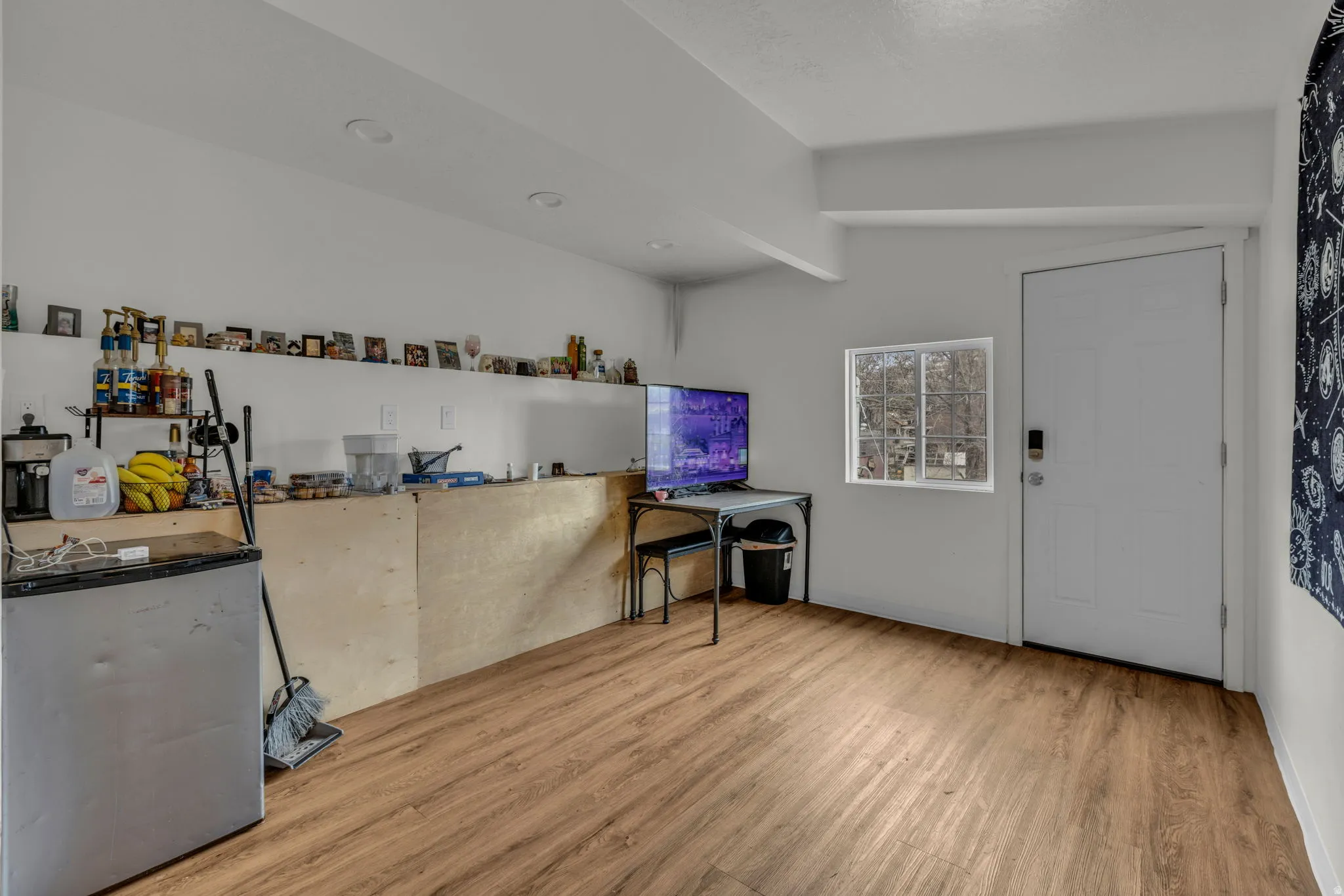Bar area featuring light wood-type flooring, lofted ceiling, and stainless steel fridge