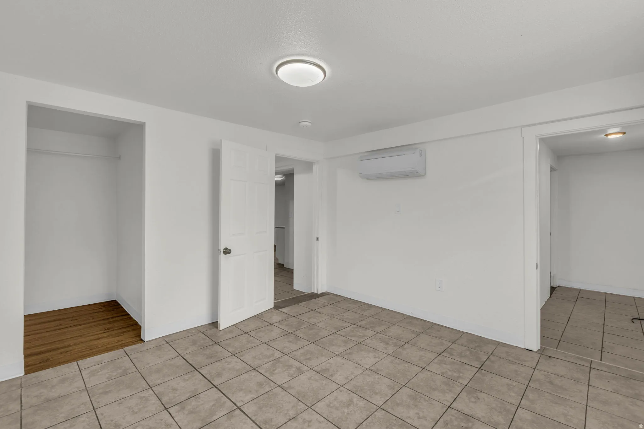 Unfurnished bedroom with light tile patterned floors and a mini split for heating / cooling
