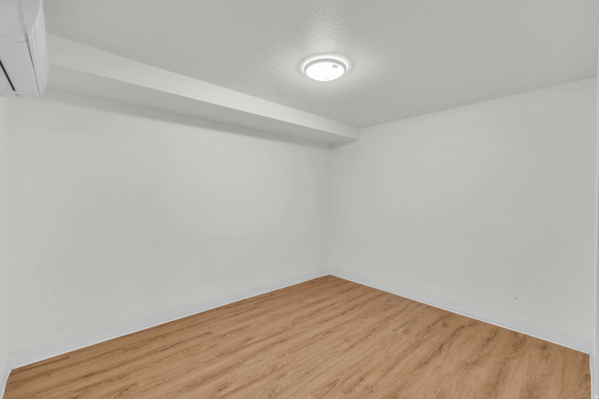 Unfurnished room with light wood-type flooring, a mini split for heating / cooling, and a textured ceiling