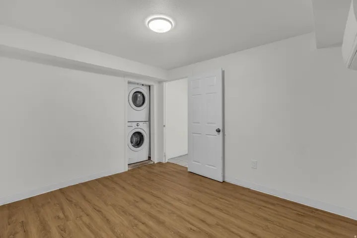 Laundry area with stacked washer / dryer and light wood finished floors