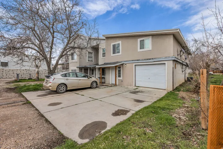 Traditional-style house with stucco siding, an attached garage, and concrete driveway