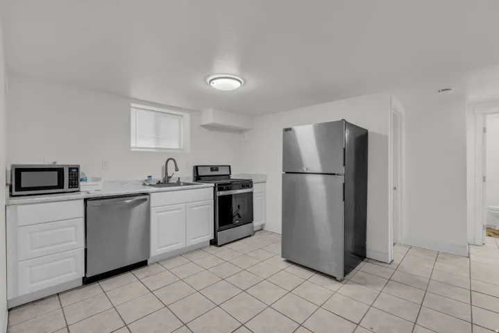 Kitchen featuring stainless steel appliances, light countertops, white cabinets, and light tile patterned floors