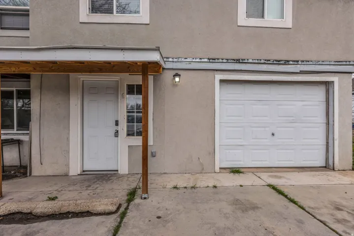 Doorway to property featuring stucco siding, a garage, and driveway