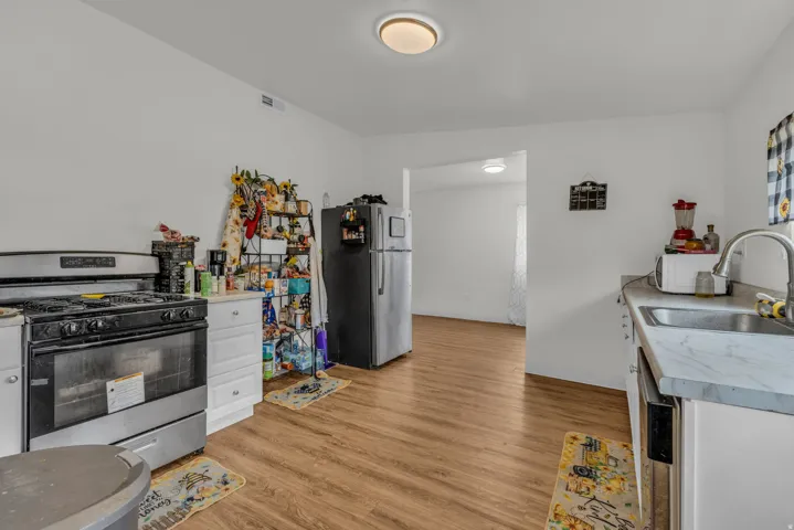 Kitchen with stainless steel appliances, light countertops, light wood-style flooring, and white cabinetry