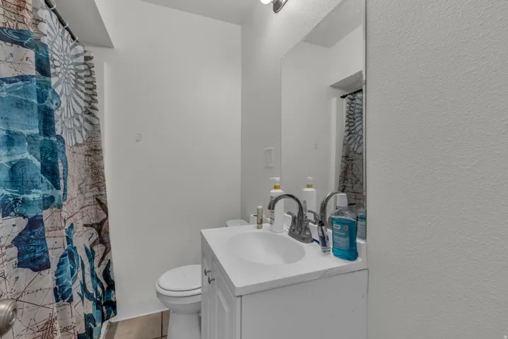 Full bathroom featuring vanity, a shower with shower curtain, a textured wall, and light tile patterned flooring
