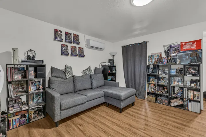 Living room with light wood-style floors and a wall mounted mini split