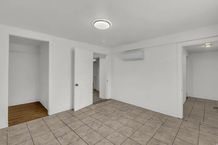 Unfurnished bedroom with light tile patterned floors and a mini split for heating / cooling