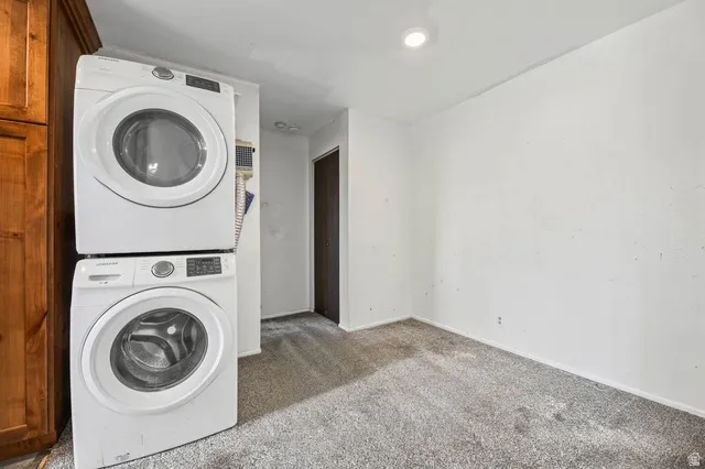 Laundry area with carpet floors and stacked washer / dryer