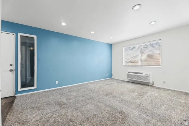 Carpeted spare room featuring a ptac unit and recessed lighting