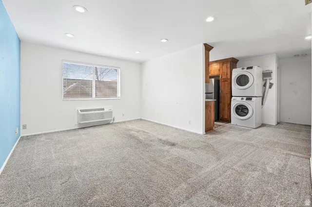 Unfurnished living room with stacked washer / drying machine, light carpet, and recessed lighting