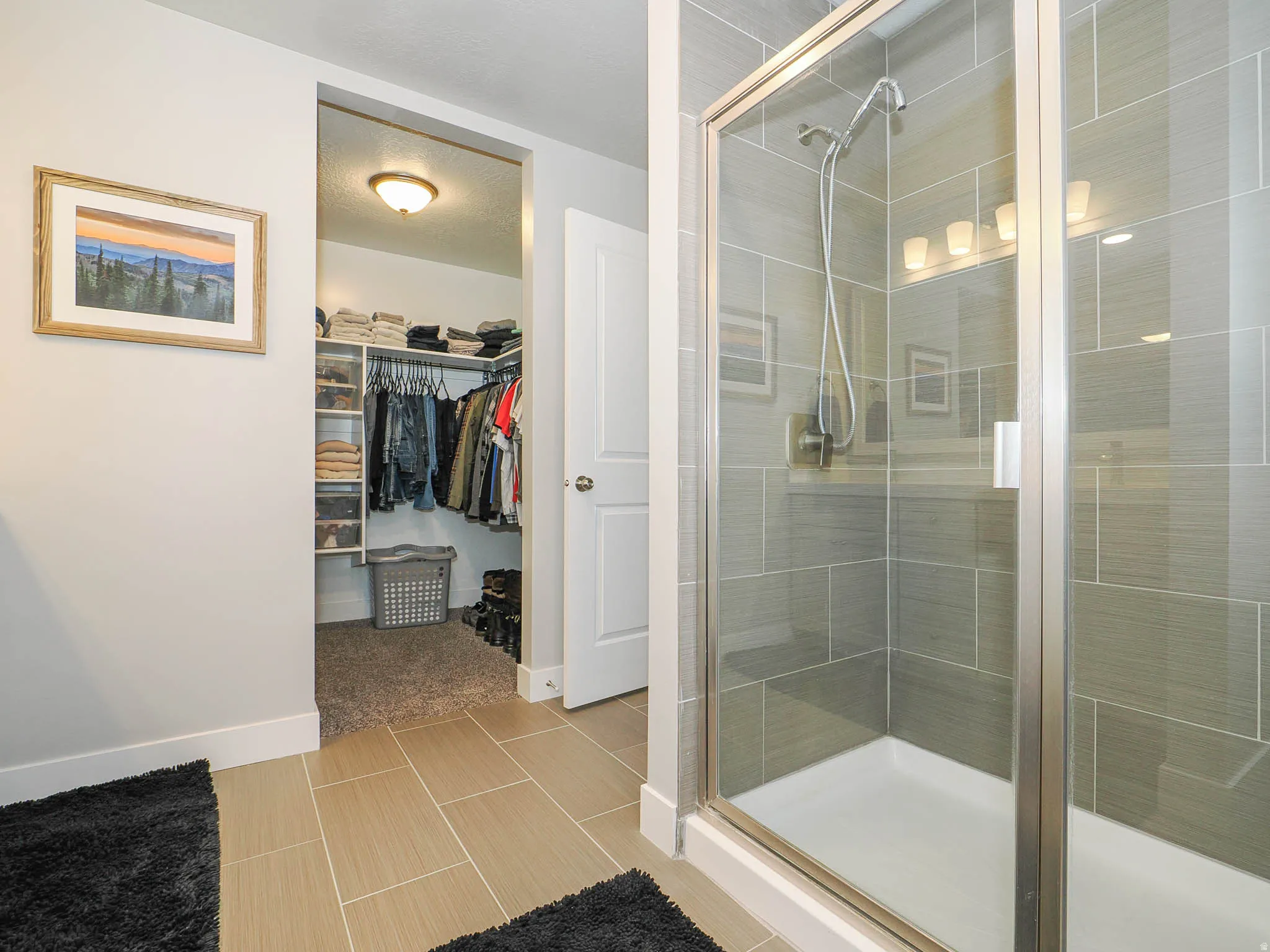Bathroom featuring a spacious closet, a shower stall, and a textured ceiling