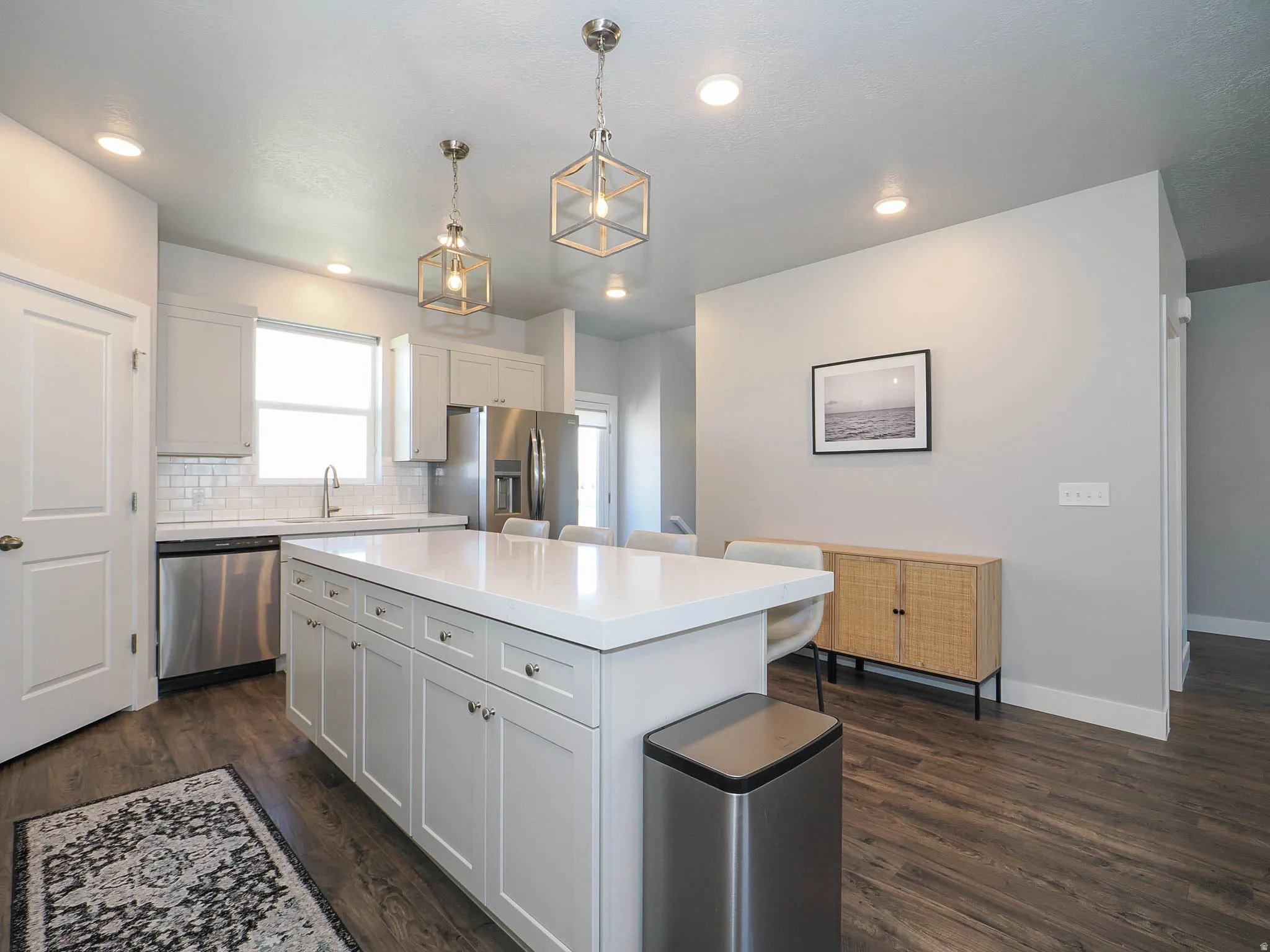 Kitchen with white cabinetry, decorative backsplash, stainless steel appliances, a breakfast bar area, and dark wood finished floors