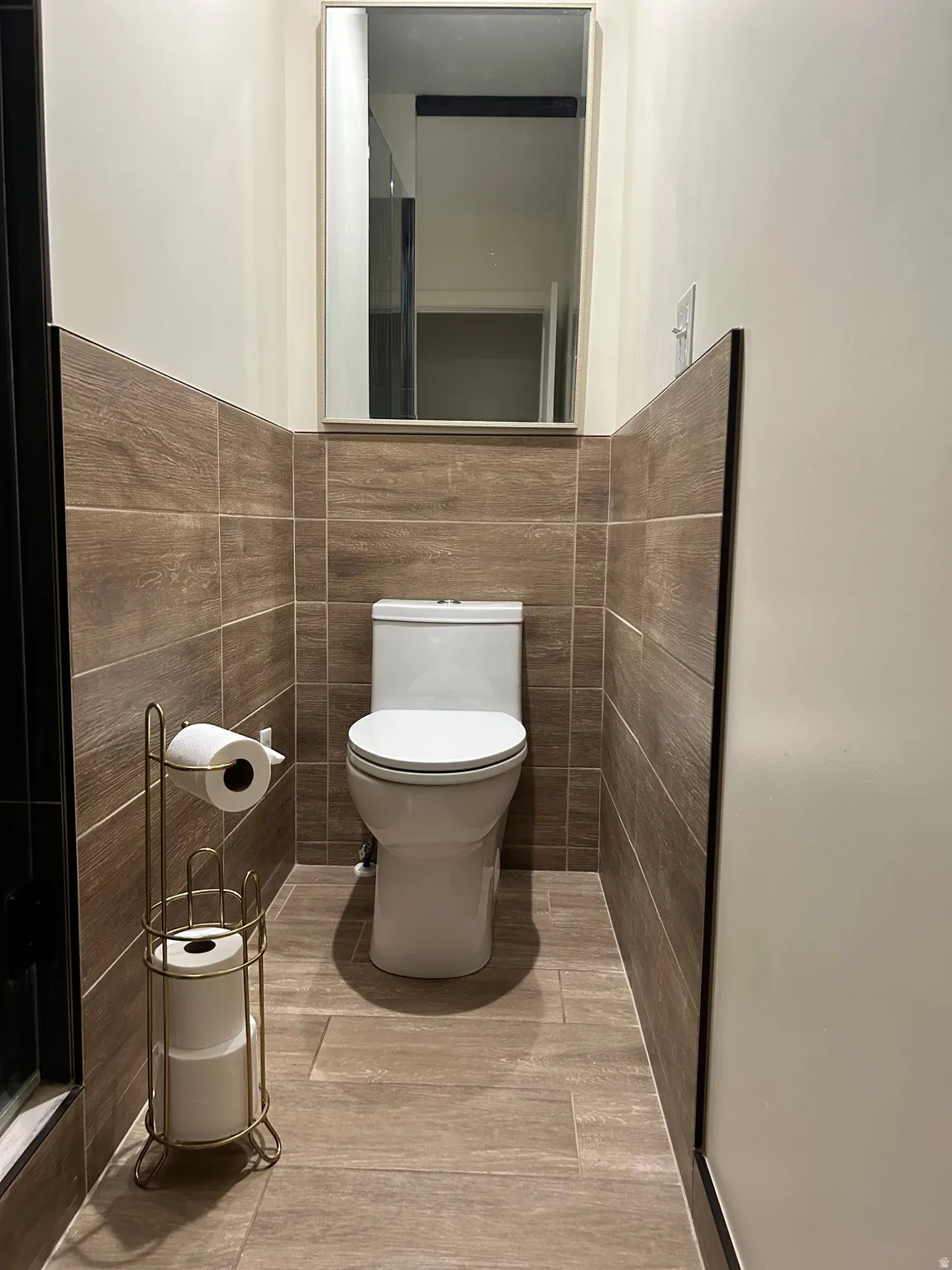 Bathroom featuring tile walls and toilet