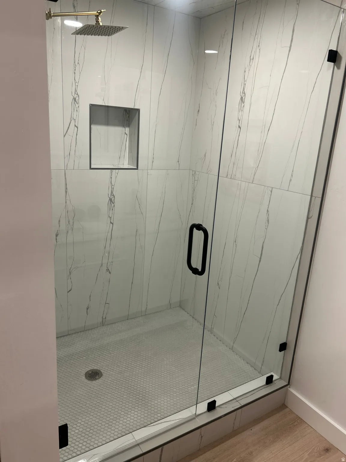 Full bath featuring a marble finish shower and light wood-style floors