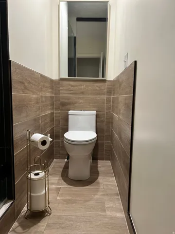 Bathroom featuring tile walls and toilet