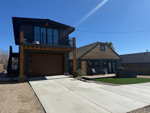 View of front of property with concrete driveway, a garage, and a balcony