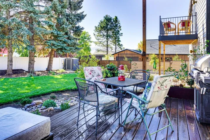 Wooden deck with outdoor dining area, a fenced backyard, and grilling area
