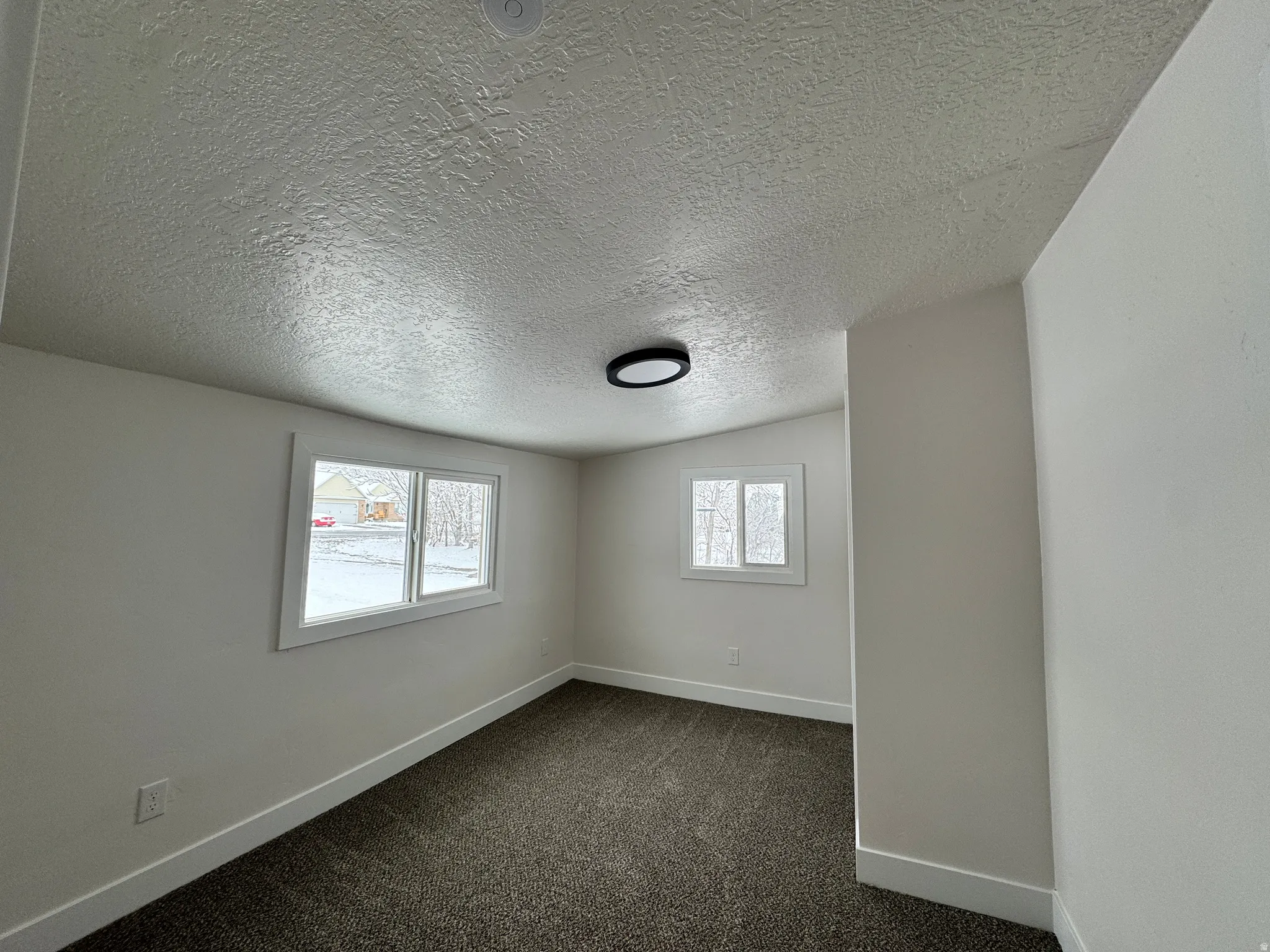 Spare room with baseboards and dark carpet