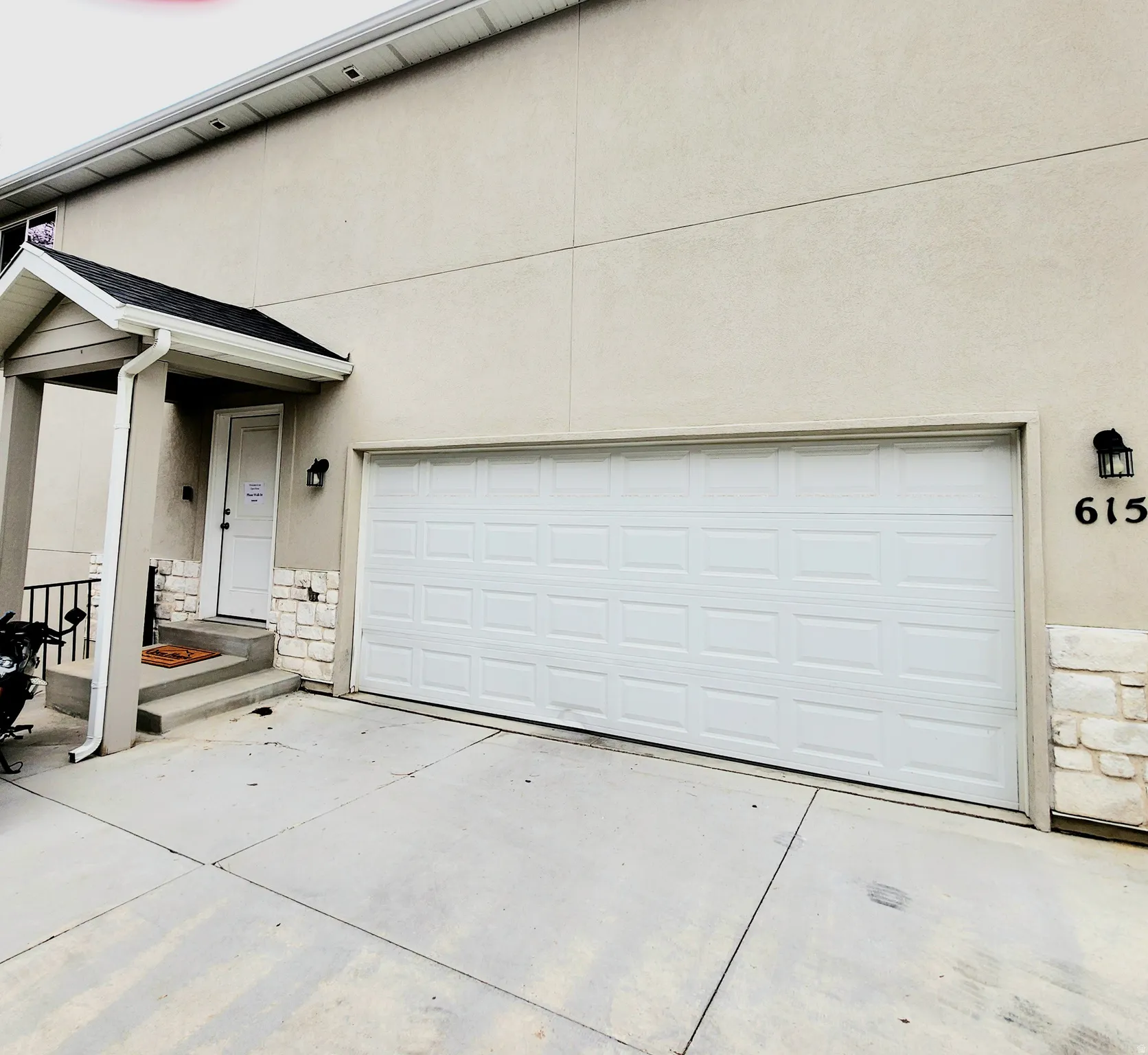 View of front of home with stone siding, stucco siding, and driveway