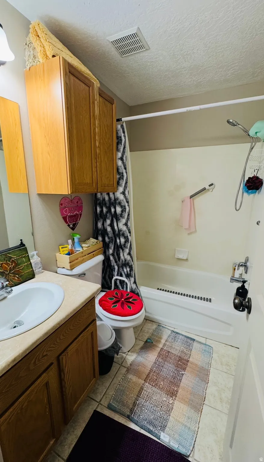 Full bathroom featuring vanity, shower / tub combo, a textured ceiling, and light tile patterned floors
