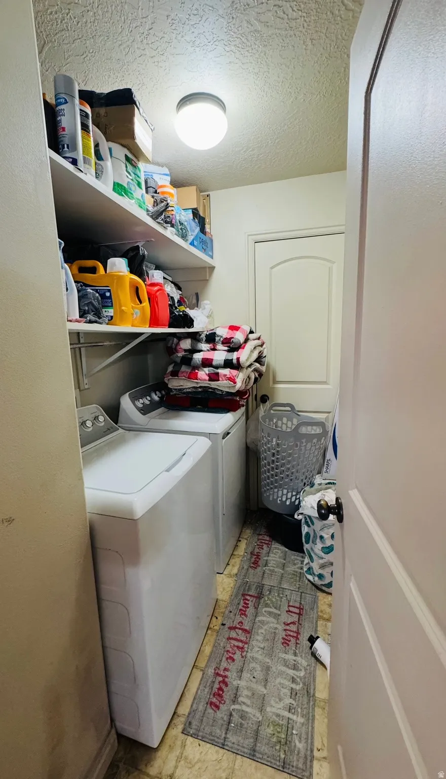 Laundry room featuring a textured ceiling and washing machine and dryer