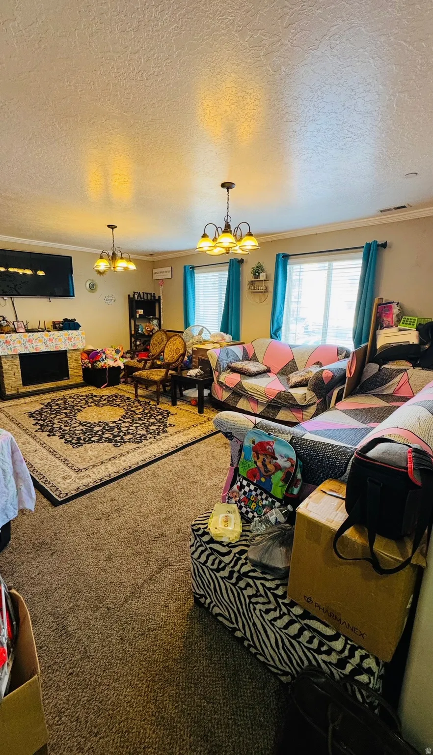 Living room featuring suspended lighting, crown molding, carpet flooring, and a textured ceiling