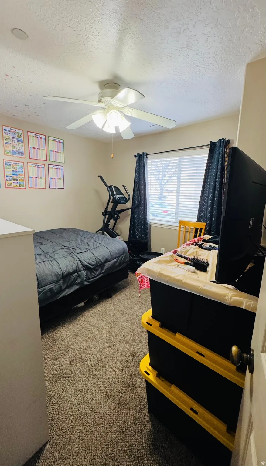 Bedroom featuring a textured ceiling, dark colored carpet, and a ceiling fan