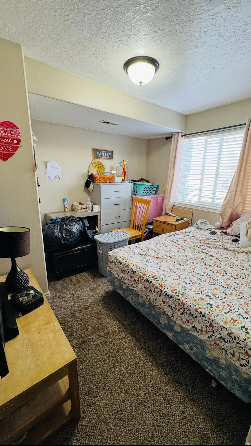 Bedroom featuring dark carpet and a textured ceiling