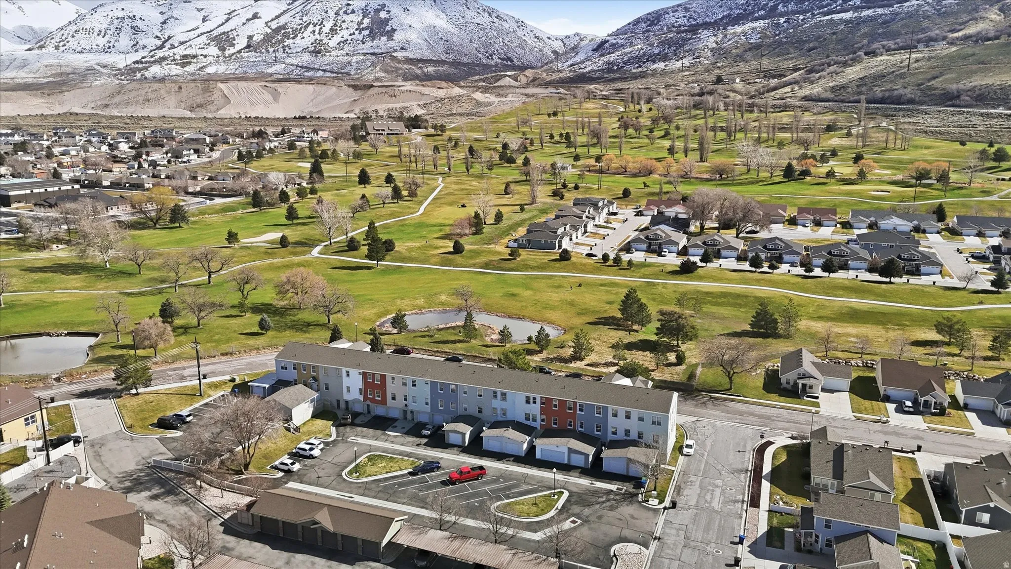 Aerial view of residential area featuring a mountain backdrop and a golf course