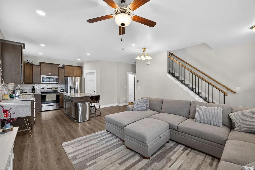 Living room featuring wood finished floors, a ceiling fan, and a chandelier